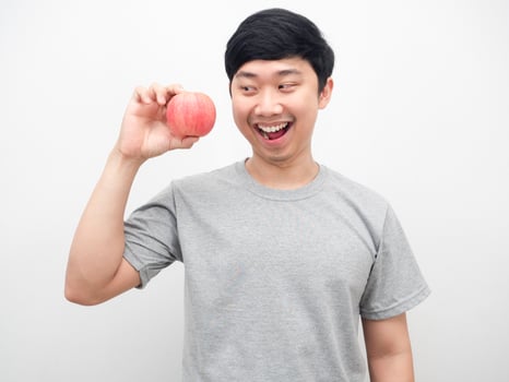 Asian man looking at red apply in hand with smiling health concept photo