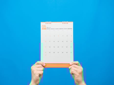 Close up hand holding calendar 2022 on blue background photo