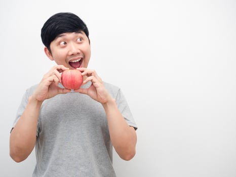 Man grey shirt gesture eatting red apply and looking at copy space photo