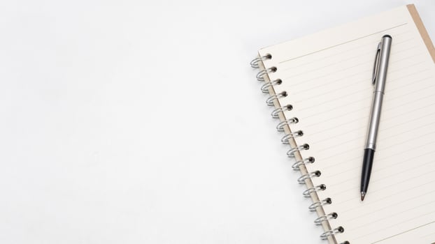 Silver pen and notebook blank page on the table top view copy space photo