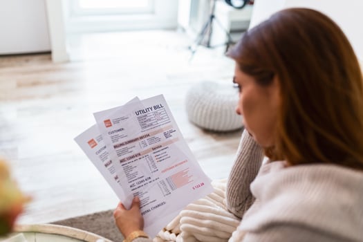 Indoor shot of casually dressed young woman holding papers in her hands, calculating family budget, trying to save some money , having stressed and concentrated look photo