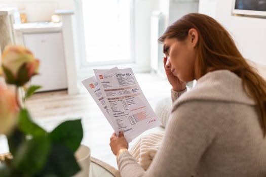Indoor shot of casually dressed young woman holding papers in her hands, calculating family budget, trying to save some money , having stressed and concentrated look photo