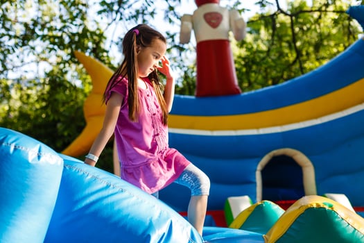Happy little girl having lots of fun on a jumping castle during sliding. photo