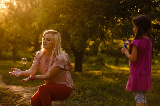 Mom and daughter blow bubbles on sunset photo