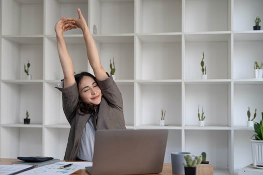 Asian businesswoman stretches her arms to relax her tired muscles from working at her desk all day at the office. photo