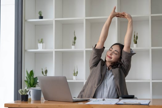 Asian businesswoman stretches her arms to relax her tired muscles from working at her desk all day at the office. photo
