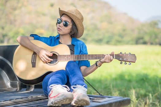 Woman wear hat and playing guitar on pickup truck photo