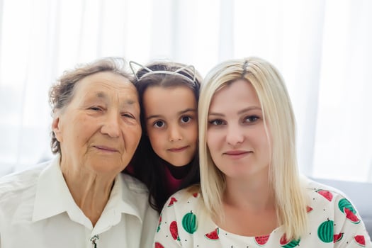 Portrait of happy little girl, her mother and grandmother looking at camera at home photo
