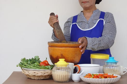 Closeup  senior woman is cooking,  wear apron, holds pestle, mortar. Concept, Cooking for family. Thai kitchen lifestyle. Elderly activity. photo