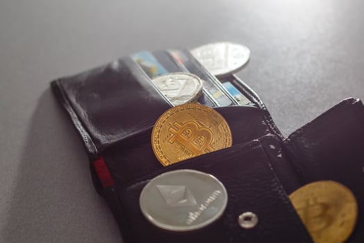 Closed wallet with dollar bills and bitcoins on the wooden table. Business concept. photo