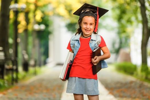 Happy school kid graduate in graduation cap looking up photo