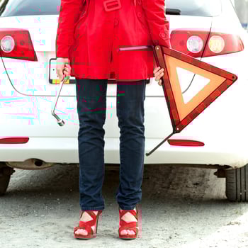 Woman holds red triangle sign and wrench and waits for roadside assistance photo