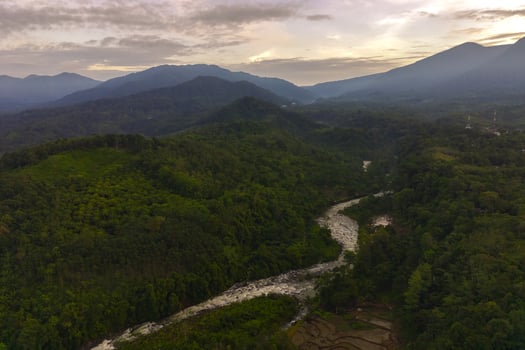 Beautiful morning view of Indonesia. Aerial photo of river between mountains and tropical forest