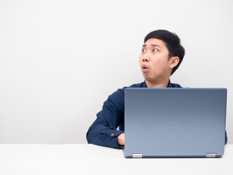 Man sitting with laptop on the table looking at copy space feeling shocked photo