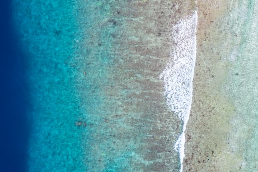 Aerial sea view, top view of amazing nature ocean background. Bright blue water colors, lagoon beach with waves splashing at sunny day. Flying drone photo, amazing nature landscape with coral reef photo