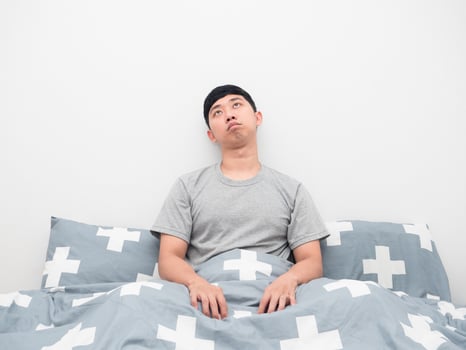 Man wake up on the bed feeling bored and looking up photo