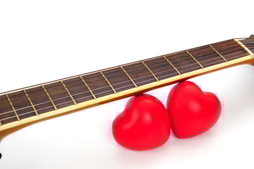 Acoustic guitar neck and red heart against white background. Love and music concept. photo