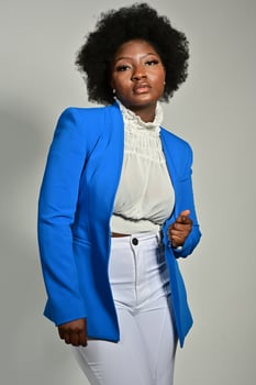 Pretty African American female with trendy accessories and Afro hairstyle looking at camera against gray background photo