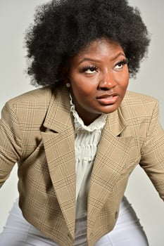 Pretty African American female with trendy accessories and Afro hairstyle looking at camera against gray background photo