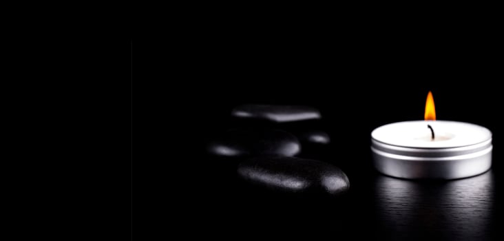 Close-up of black stones and candle on black background. Lifestyle concept photo