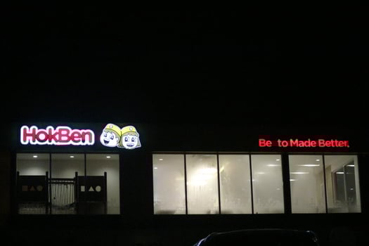 Bekasi, Indonesia in July 2022. Hokben or Hoka Hoka bento logo shining brightly at night against the dark night sky. photo