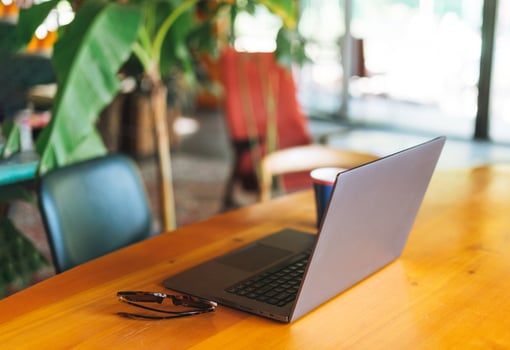 Open laptop on table in cafe, paper cup with coffee and sunglasses. The concept of freelance and remote work photo
