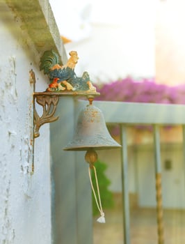 Small iron bell with colored rooster outside the house. photo
