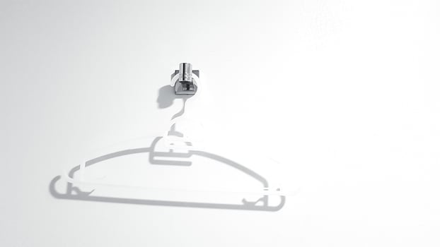 White plastic clothes hanger hanging on white wall with copy space. Object for clothing. photo