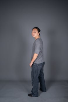 Asian long hair friendly and positive man is posting and standing in front of gray background with studio light. photo