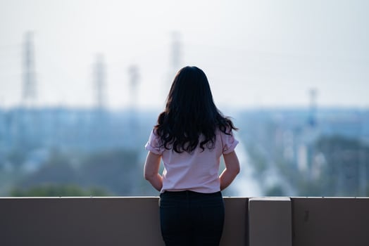 Asian female teen stands backside in front of city view at rooftop of the building photo
