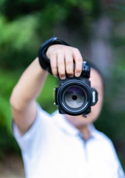Asian man holds the Medium Format Camera in his hand and focus to shoot in front of him. photo