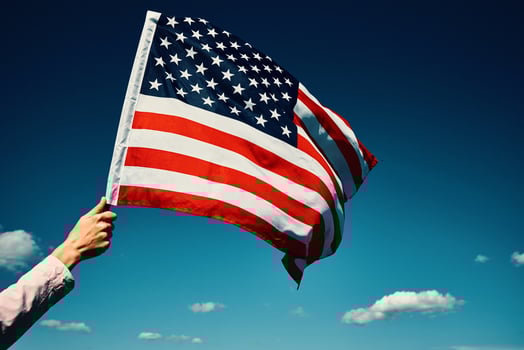 Waving usa flag in hand against blue sky photo