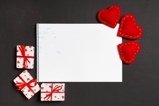 Top view of notebook surrounded with gift boxes and hearts on colorful background. Valentine's Day concept photo