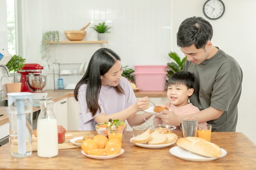 activities together during the holidays. Parents and children are having a meal together during the holidays. boy is teasing his father by giving him bread and vegetables. photo