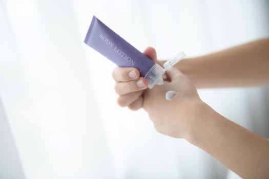 Close up of women applying body lotion cream on hand. photo