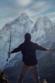 A silhouette of a man in Nepal is overlooking the Ama Dablam mountain in the Dingboche village into the blue and cloudy sky with a big snow-capped mountain. photo