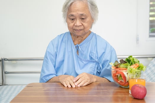 Asian senior or elderly old lady woman patient eating Salmon steak breakfast with vegetable healthy food while sitting and hungry on bed in hospital. photo