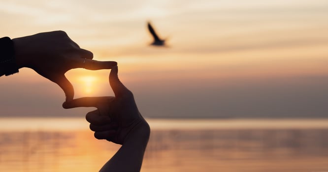Planning and vision concept of new year's start, woman hands making frame gesture find focus at sunset, woman looking for perspective to capture the meaning of a clear upcoming target. photo