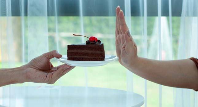 The woman refuses to eat the chocolate cake on the hand. Stop eating sweets to lose weight photo
