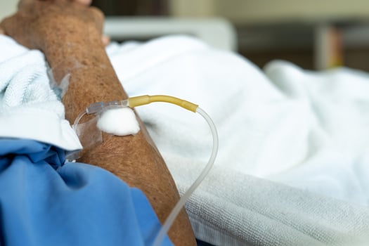 an elderly man's arm wearing a patient's uniform is lying in a saline bed in a hospital bed. illness, treatment and recovery concept photo