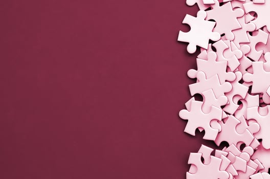 A pile of uncombed elements of a white jigsaw puzzle lies on the background of surface. Texture photo with copy space for text Image toned in Viva Magenta, color of the 2023 year