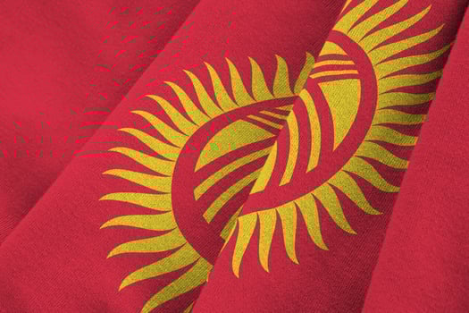 Kyrgyzstan flag with big folds waving close up under the studio light indoors. The official symbols and colors in banner photo