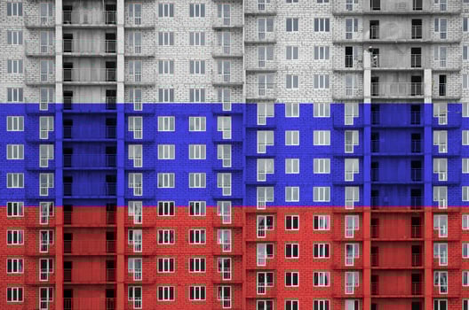Russia flag depicted in paint colors on multi-storey residental building under construction. Textured banner on brick wall background photo