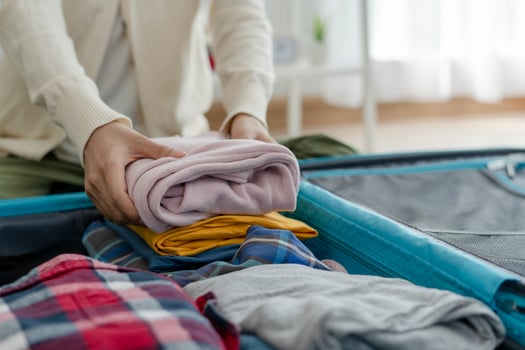 Travel bags for vacation trips. A young woman prepares clothes and personal items to put in her suitcase. Pack your bags before traveling photo