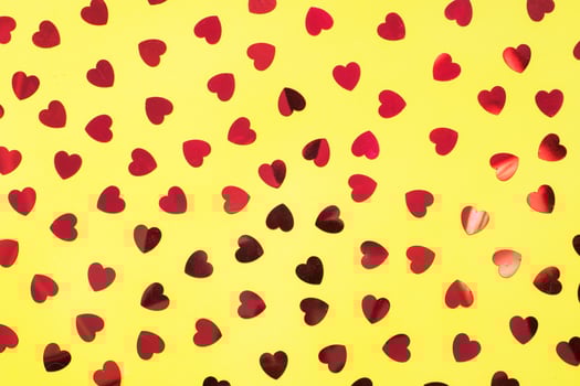 Festive background with red confetti hearts on yellow. Close up Top view Concept Of Valentine's Day. photo