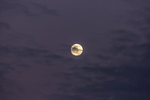 Image of full moon against colorful evening sky with light clouds photo