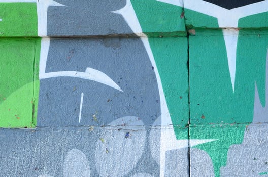 Fragment of graffiti drawings. The old wall decorated with paint stains in the style of street art culture. Colored background texture in green tones photo