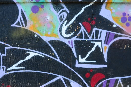 Fragment of graffiti drawings. The old wall decorated with paint stains in the style of street art culture. Colored background texture photo