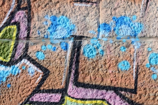 Fragment of graffiti drawings. The old wall decorated with paint stains in the style of street art culture. Colored background texture in warm tones photo