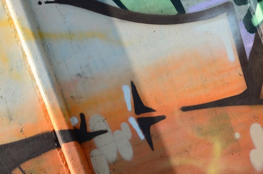Fragment of graffiti drawings. The old wall decorated with paint stains in the style of street art culture. Colored background texture in warm tones photo